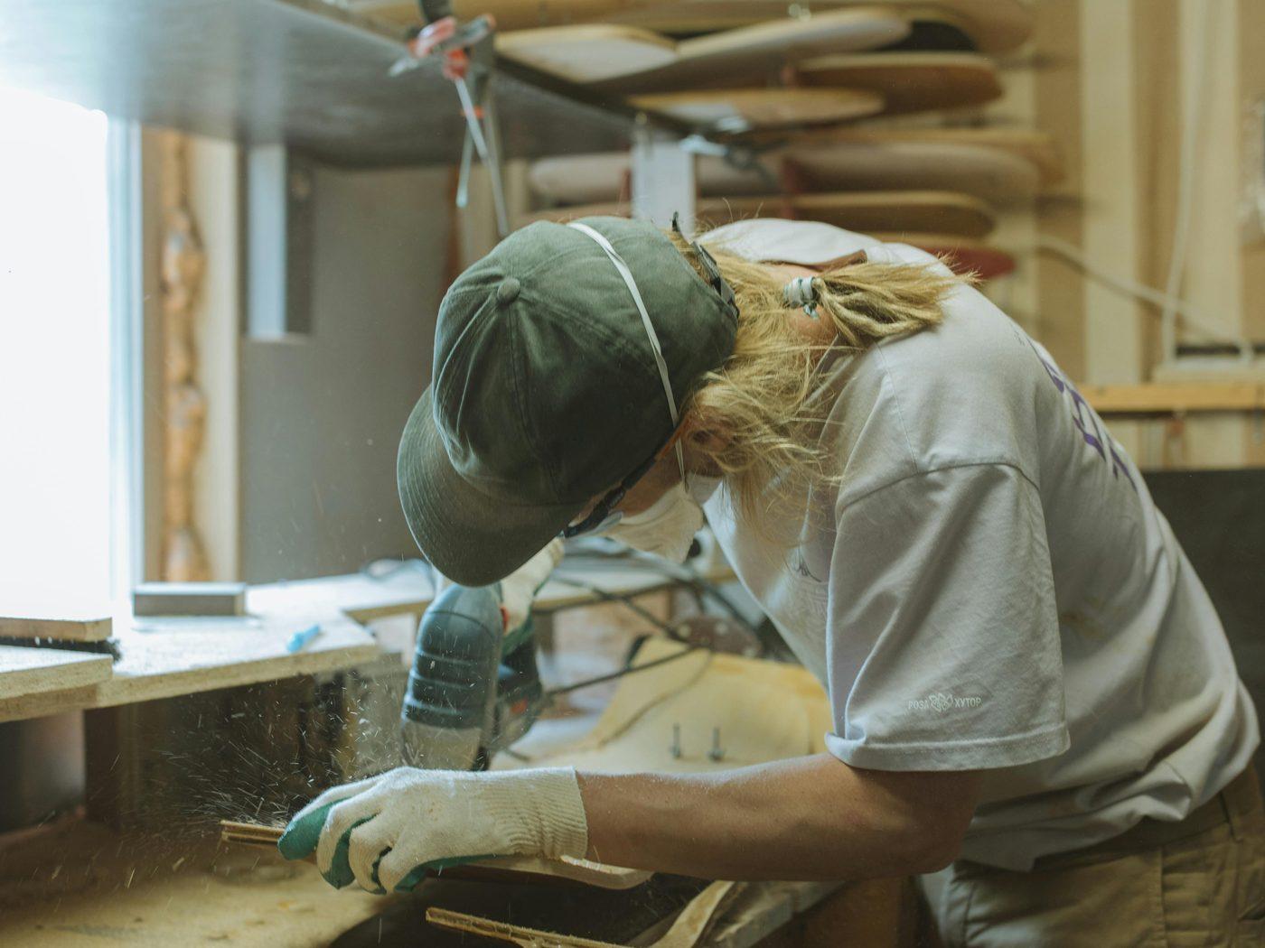 Un artisan ponce une planche de surf dans son atelier