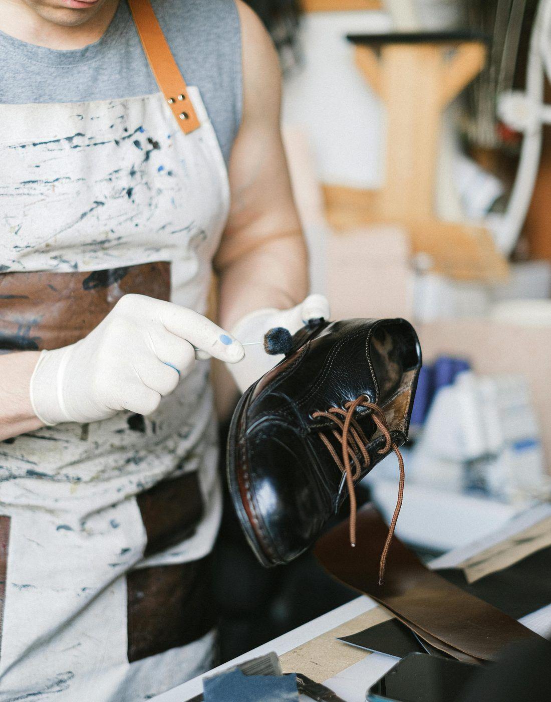 Un cordonnier lustre une chaussure en cuir dans son atelier